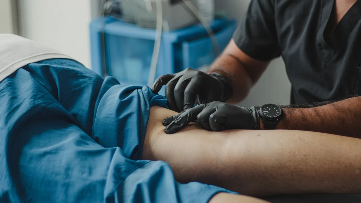 A healthcare professional in gloves provides treatment to a patient in a medical setting.