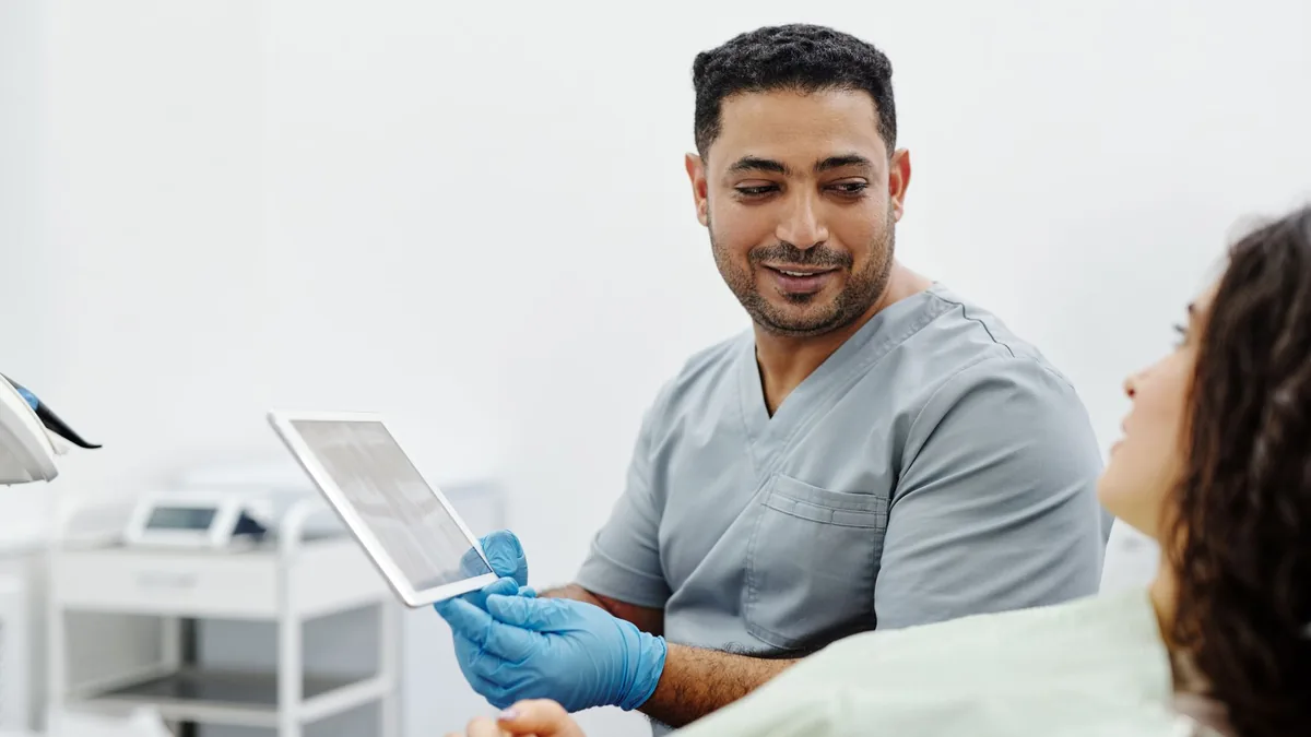 Nurse uses digital tablet for patient consultation and diagnosis in a clinical setting.