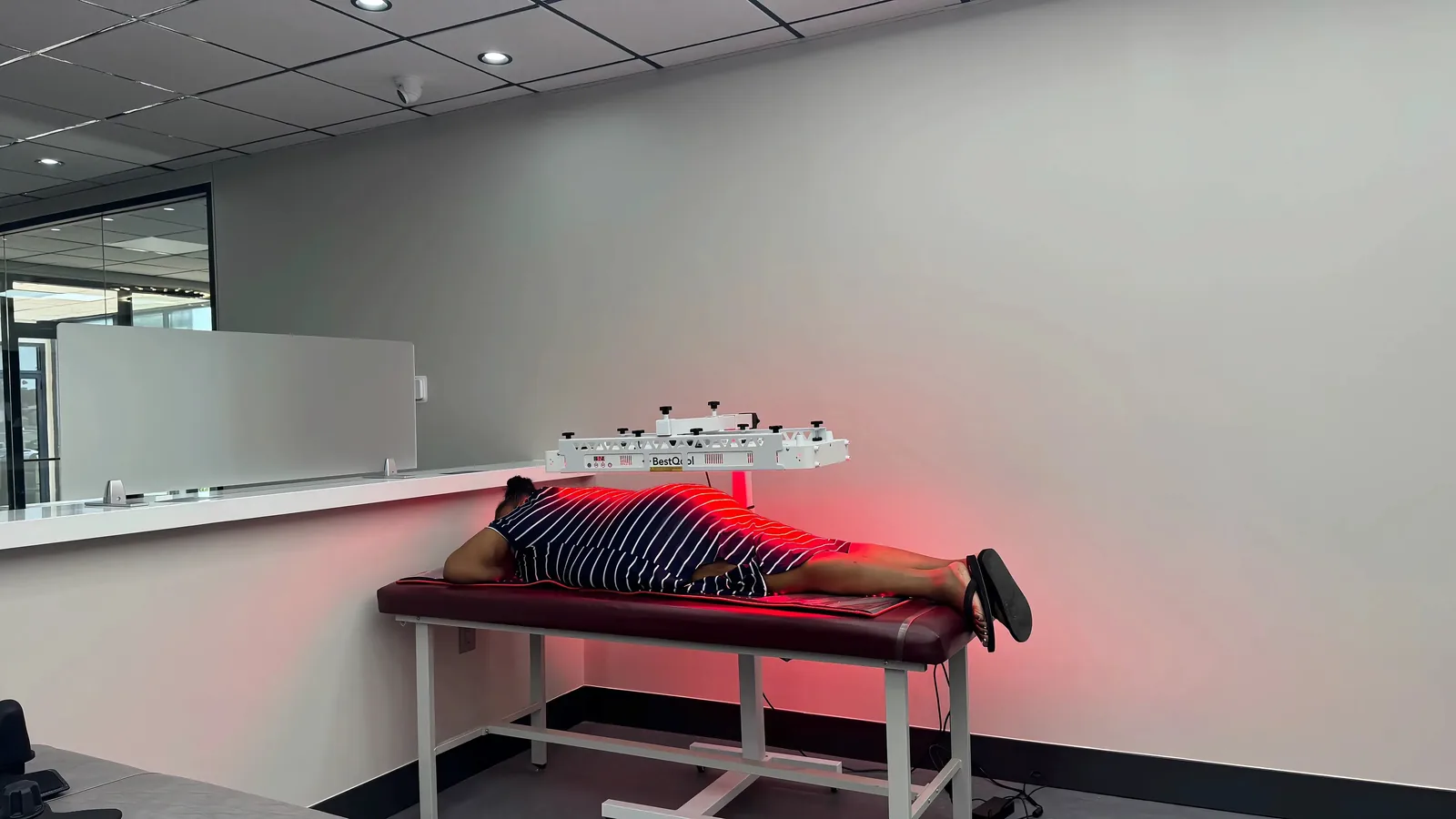 Patient receiving class 4 photobiomodulation therapy under a red-light panel on a treatment table at Regenerve, 4477 Woodson Rd #104, St. Louis, MO 63134