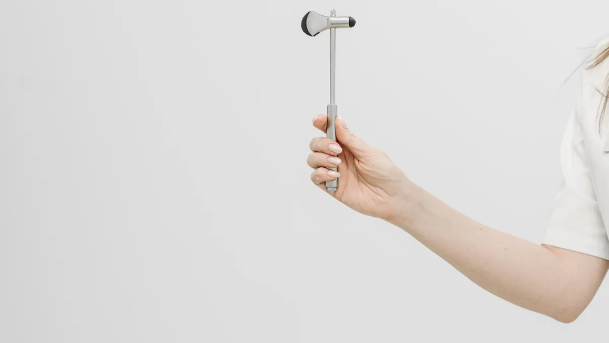 A clinician holds a reflex hammer, used to check the reflexes that are lost early in CIDP